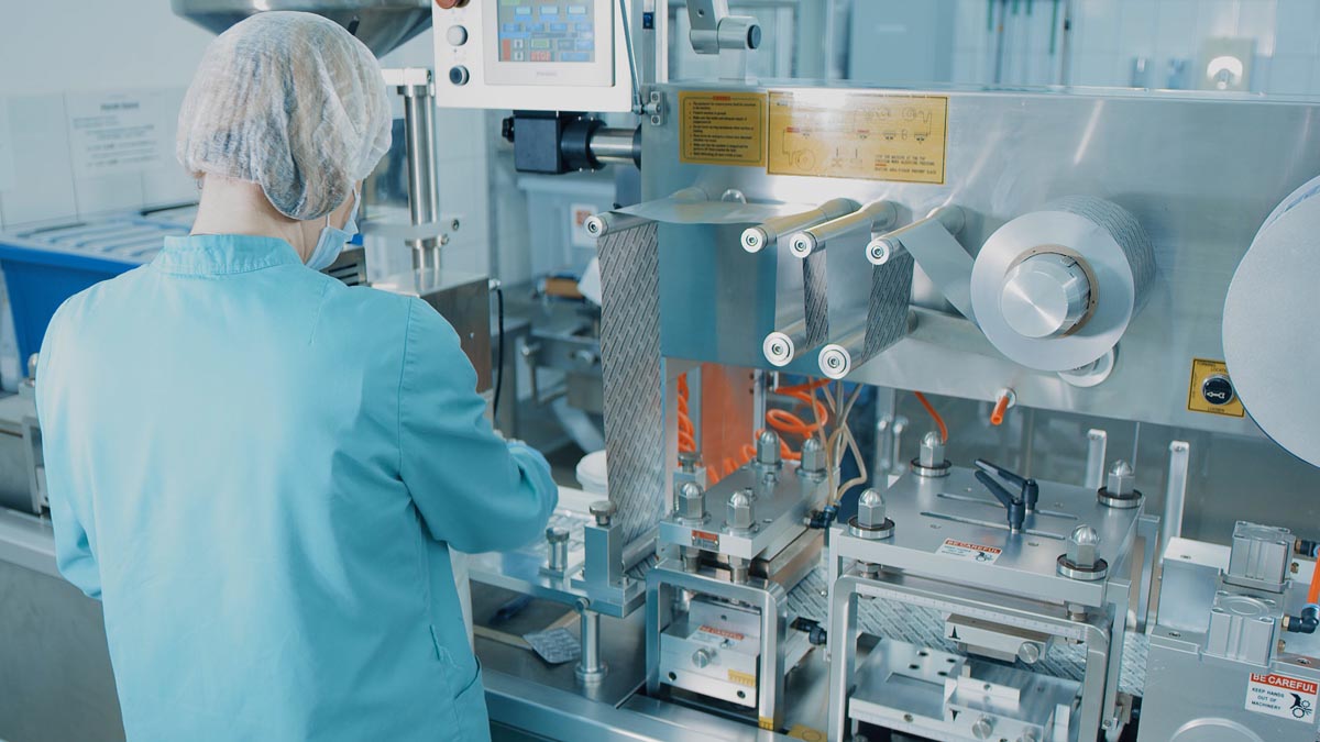 4K Blister Packing Machine. Woman works at the workplace. Tablet pharmaceutical blister packaging machine in supplement drug manufacture. Pharmaceuticals production line Maschinenbau Chemie/Pharma-Branche